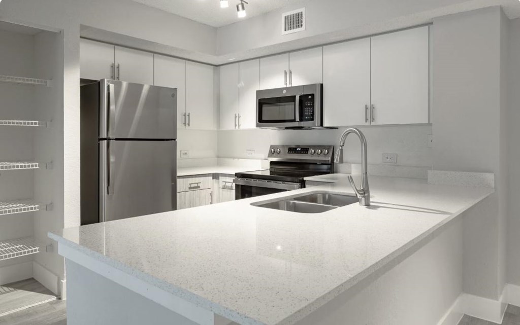 A modern kitchen with a stainless steel refrigerator and a granite countertop.
