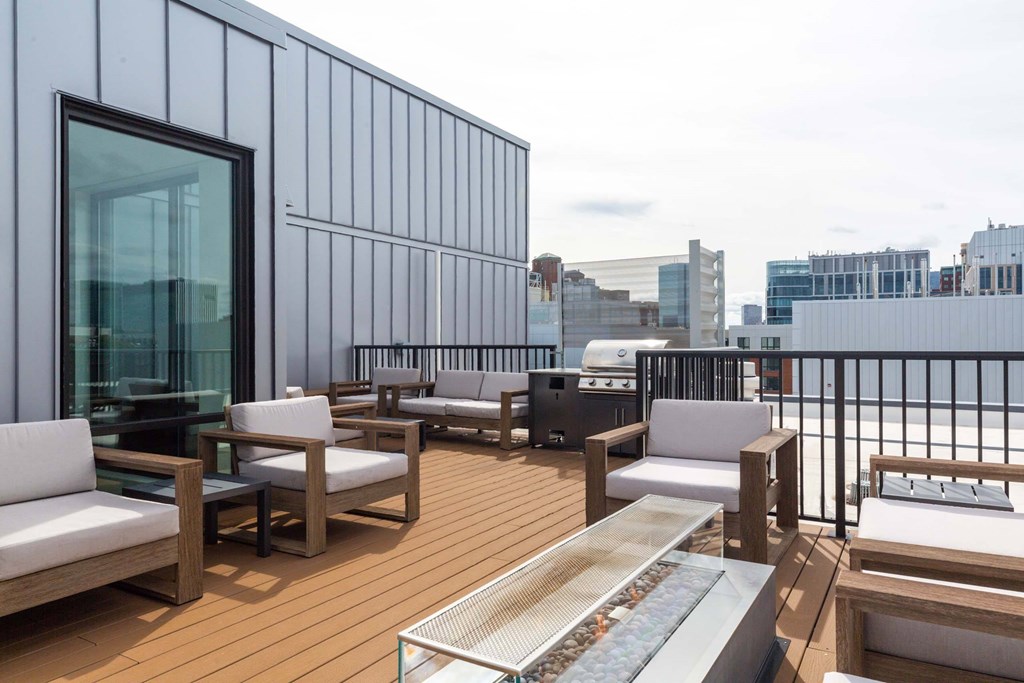 A rooftop patio with a glass table and chairs.