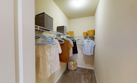 a walk in closet with clothes hanging on a rack