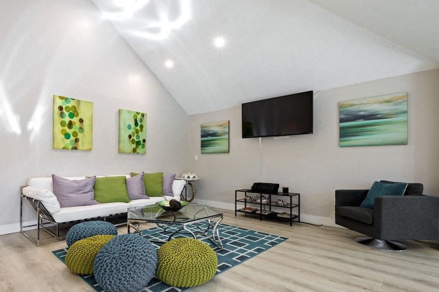 Clubhouse with couch, coffee table, rug, bean bag chairs and mounted television on wall