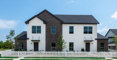 A white house with a black roof and a white picket fence.