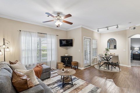A living room with a grey couch and a ceiling fan.