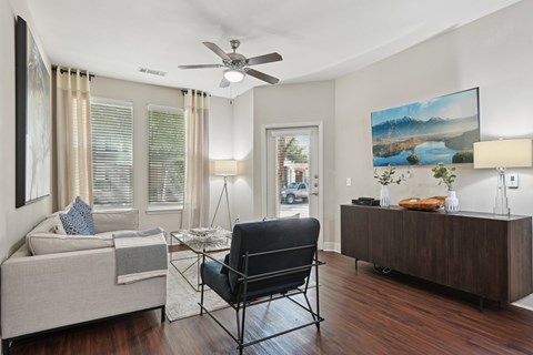 A living room with a black chair and a painting of a lake.