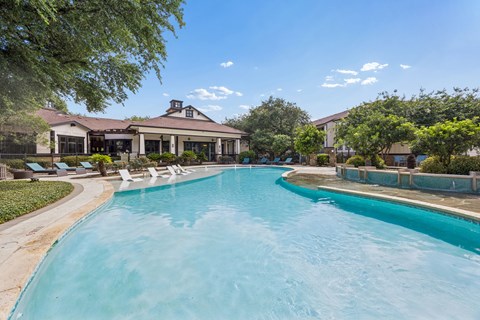 A large swimming pool in front of a house with a sunny sky.