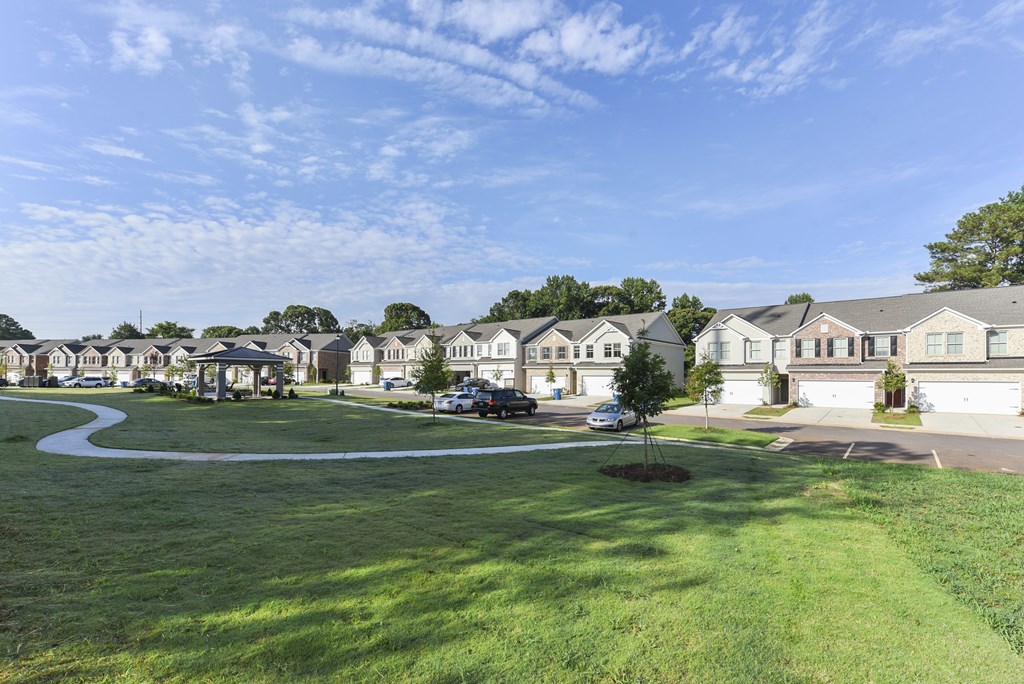 a row of houses on a street with a green lawn