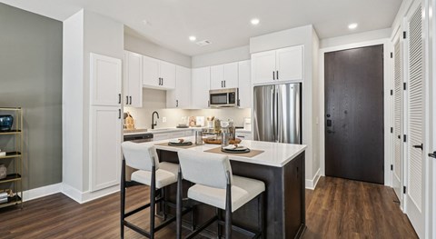 A modern kitchen with white cabinets and a wooden floor.