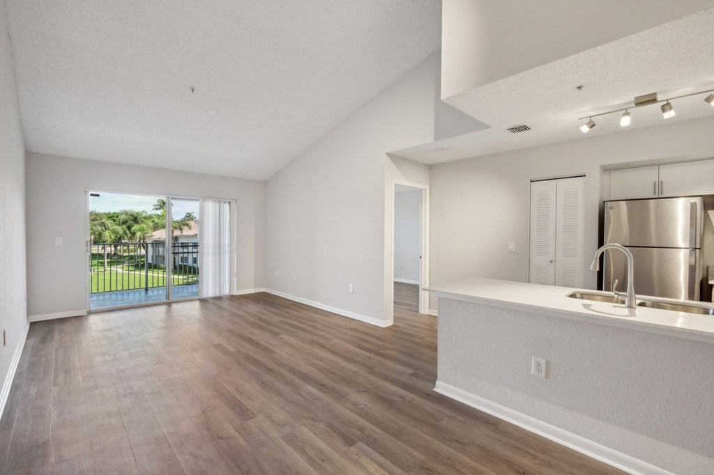 A spacious kitchen with a sink and a window overlooking a green area.