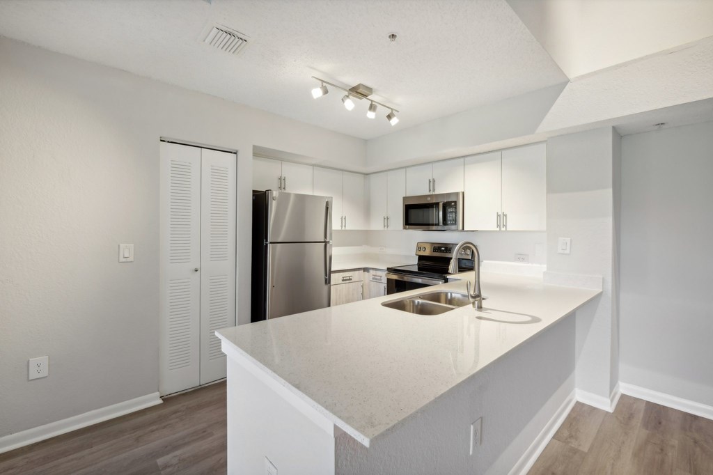 A kitchen with white cabinets and a stainless steel refrigerator.