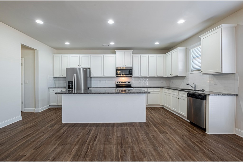 an open kitchen with white cabinets and a large island in the middle