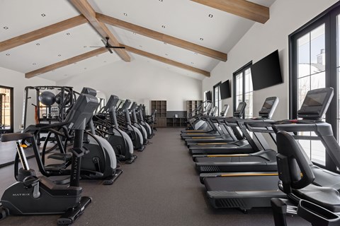 A gym with a row of treadmills and elliptical machines.