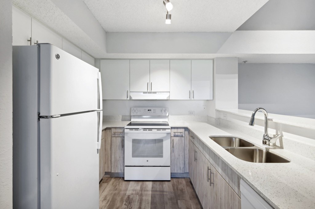 A modern kitchen with a white refrigerator, stove, and sink.