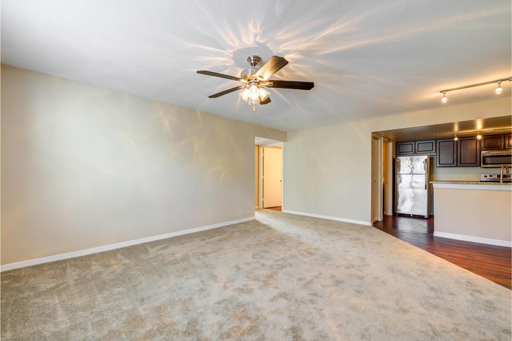 an empty living room with a ceiling fan