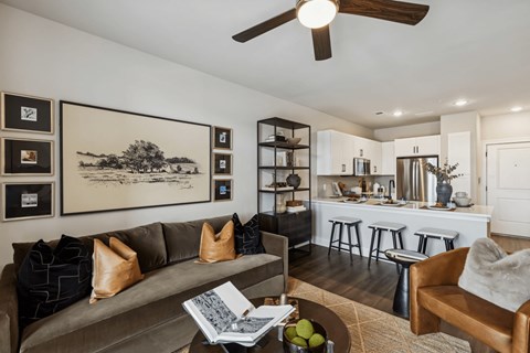 A living room with a grey couch and a coffee table with a book and fruit on it.