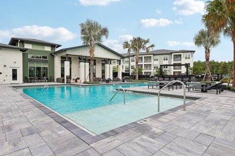 A swimming pool surrounded by a tiled floor and palm trees.