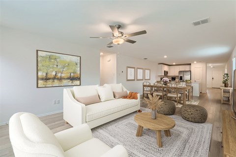 A living room with a white couch and a painting on the wall.
