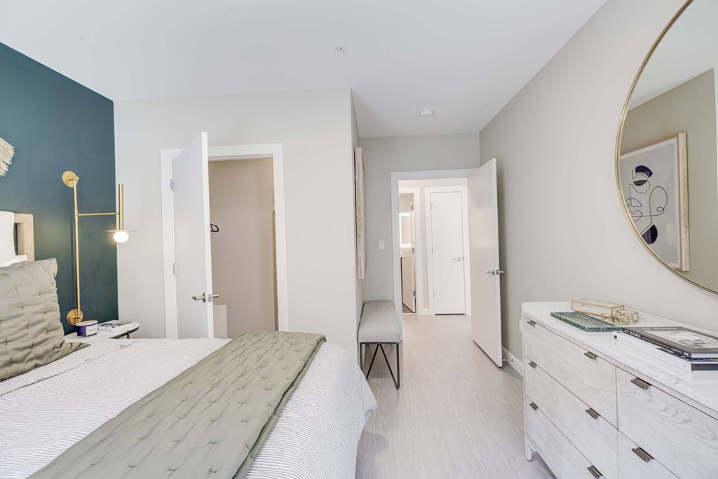 A bedroom with a bed, dresser, and mirror.