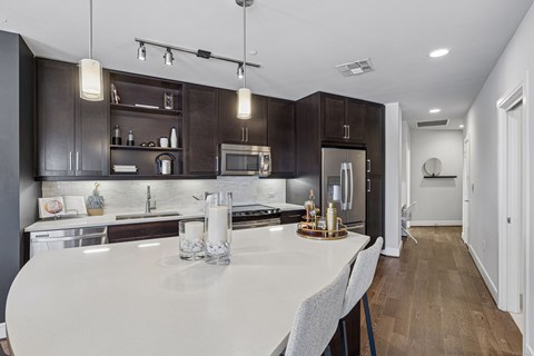A modern kitchen with dark brown cabinets and a white countertop.