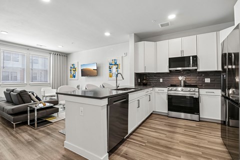 A modern kitchen with white cabinets and a wooden floor.
