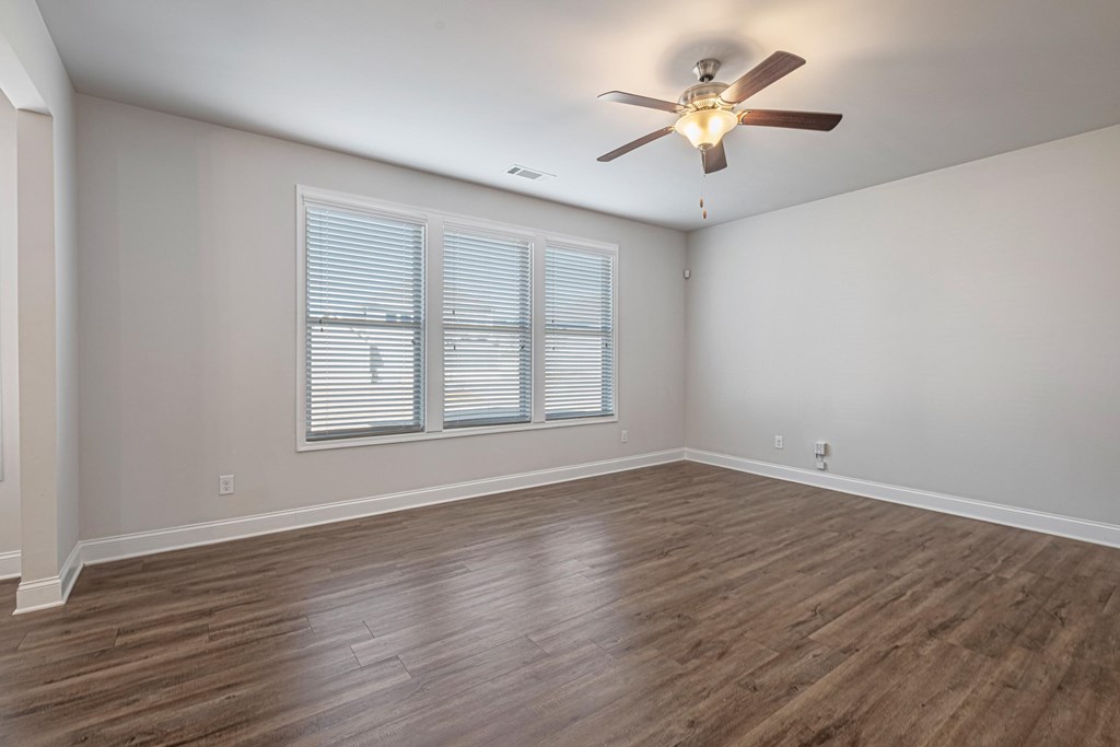 an empty living room with a ceiling fan and a window