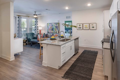 A kitchen with a white counter top and a refrigerator on the right side.