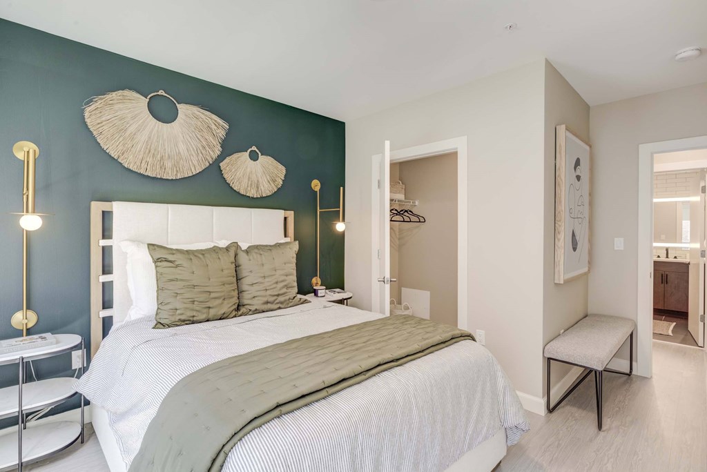 A bedroom with a bed, a bench, and a mirror.