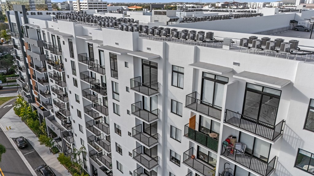 A white apartment building with balconies and cars parked on the street.