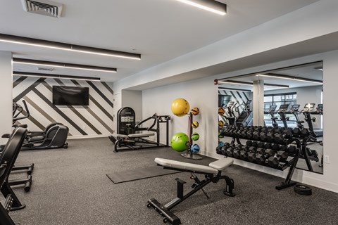 A gym with a variety of equipment including weights and exercise balls.