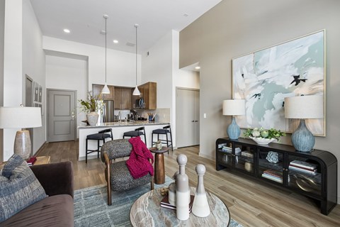 A modern living room with a grey couch, a grey chair, a coffee table, and a large painting on the wall.
