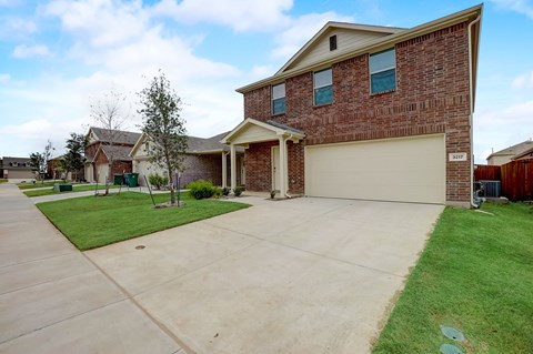 Extended driveway with a sizable lawn, offering ample space and a welcoming exterior
