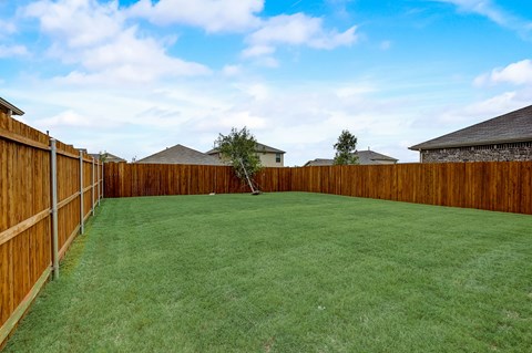 Large backyard,  surrounded by a sturdy wooden fence, creating a well-maintained and private outdoor space