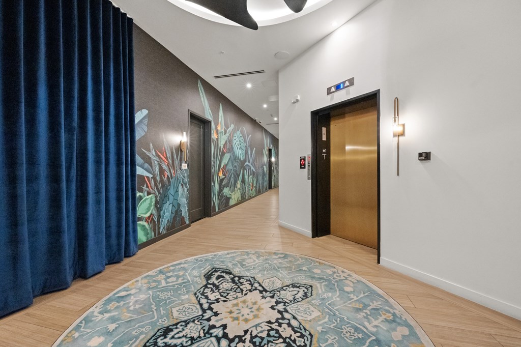 A hallway with a blue carpet and a mural on the wall.