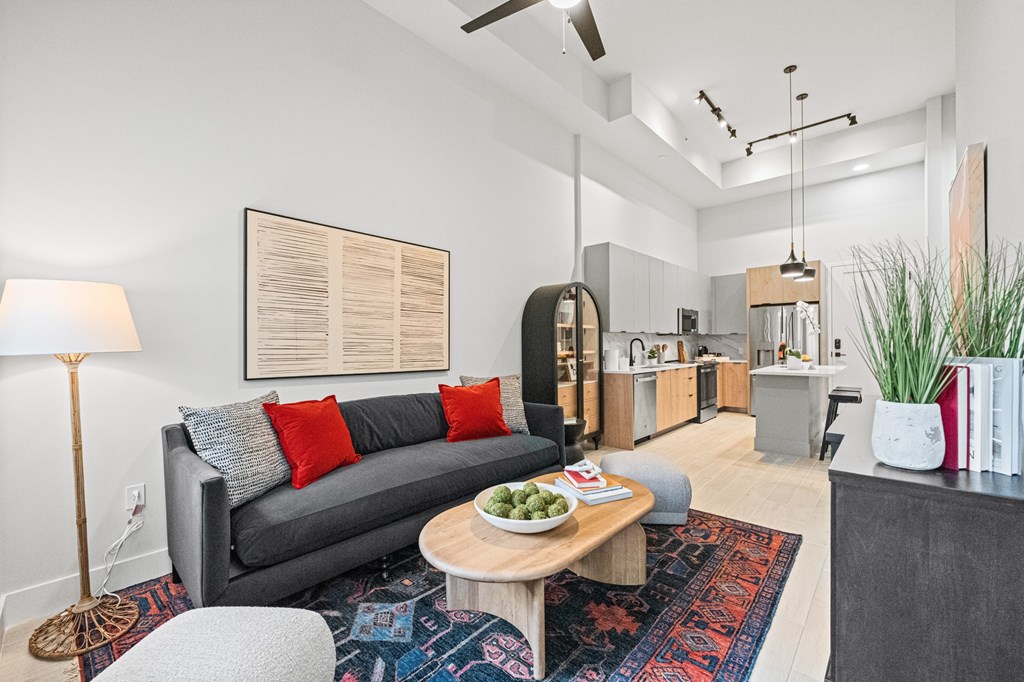 A modern one bedroom living room with a grey couch, a wooden coffee table, and a large abstract painting on the wall.