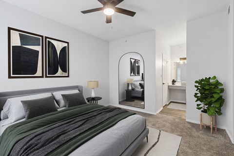 A bedroom with a bed, a ceiling fan, and a mirror.
