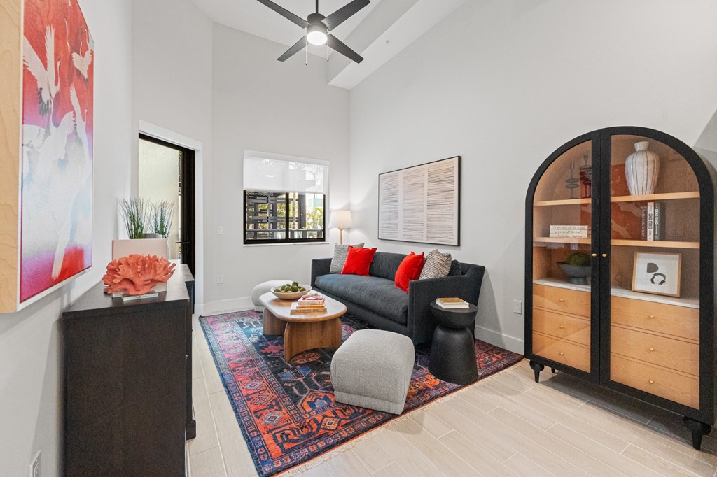 A living room with a grey couch and a red rug.