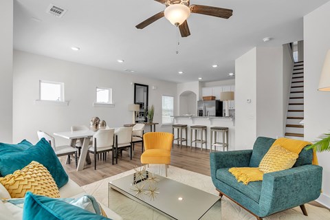 A living room with a blue chair and yellow pillow.