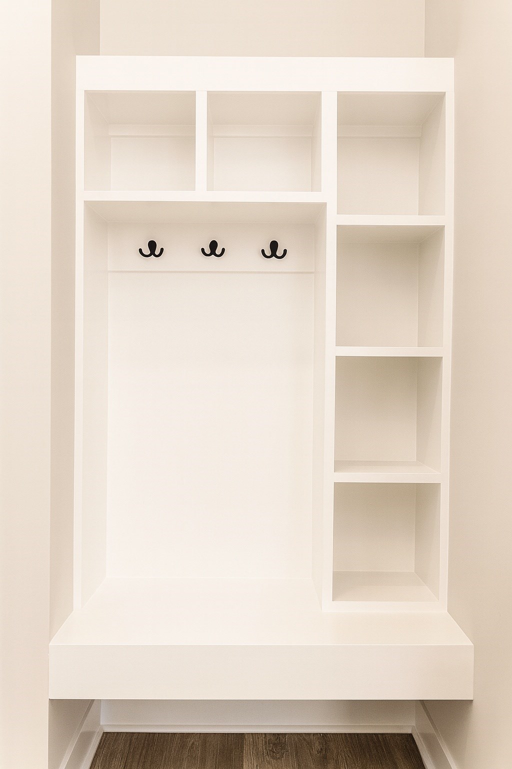 A white shelf with three hooks on it.
