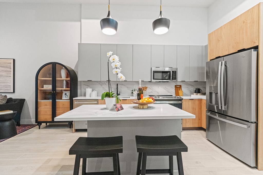 A modern kitchen with a white island and black stools.