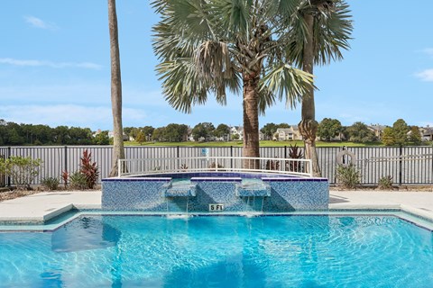 A pool surrounded by palm trees and a fence.