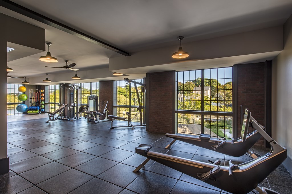 A spacious gym with a view of the outdoors through large windows.