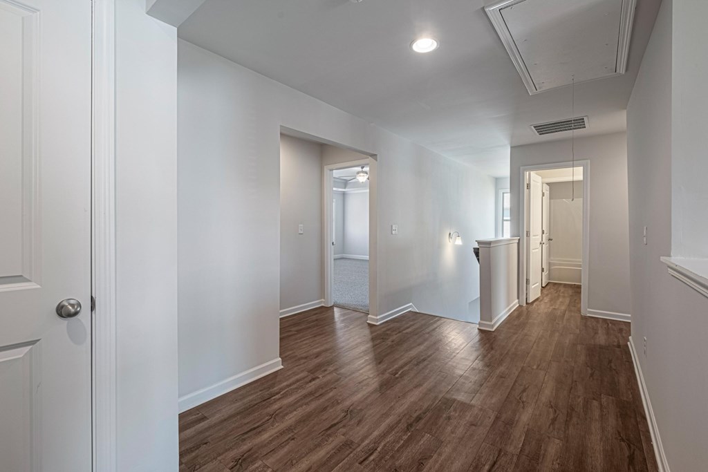 a renovated living room and hallway with white walls and wood flooring
