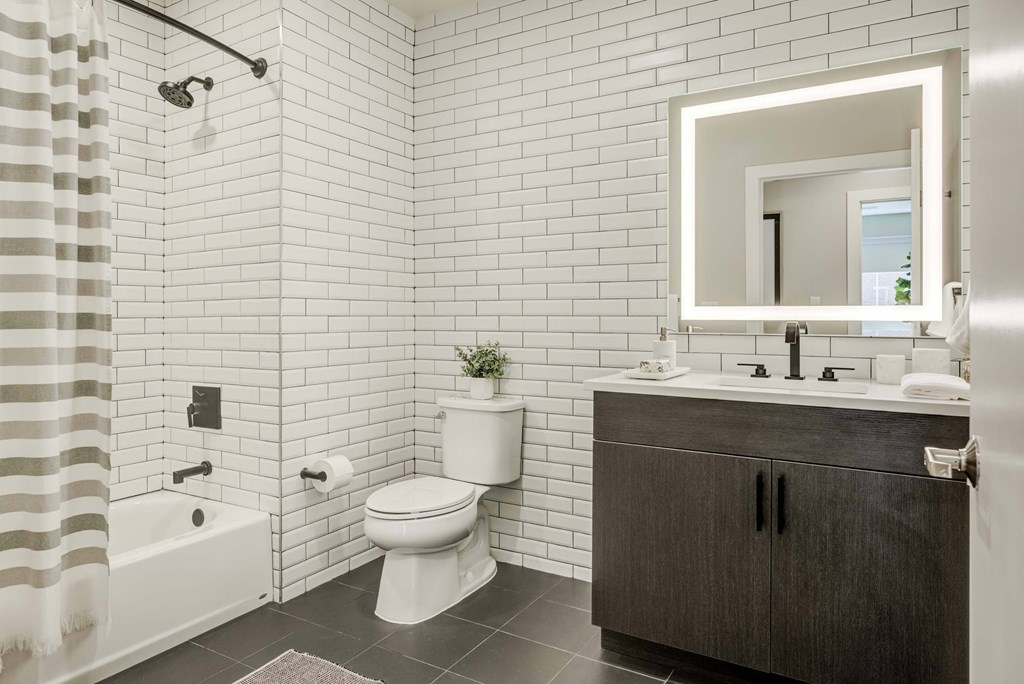 A bathroom with a toilet, sink, and mirror.