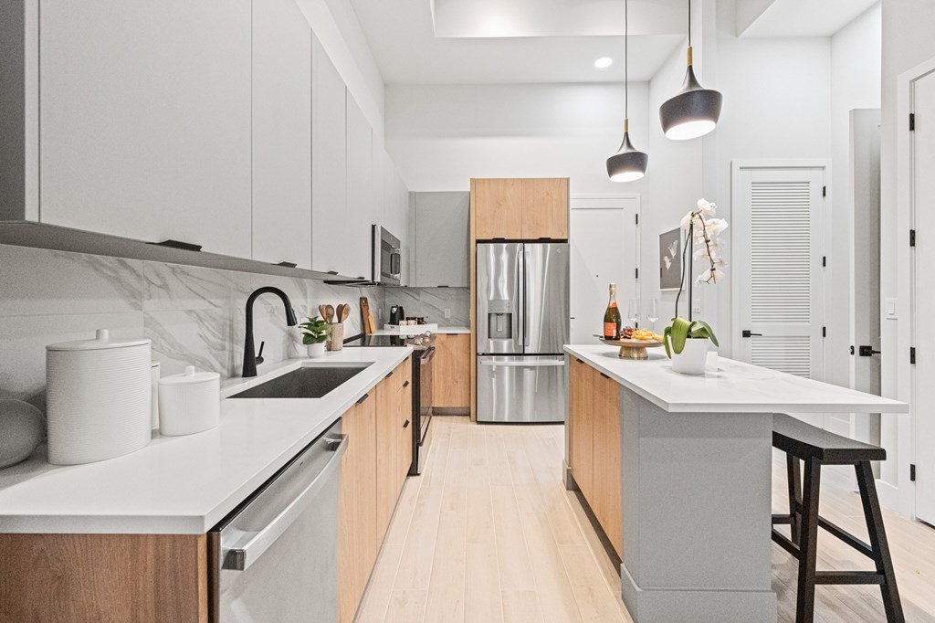 A modern kitchen with a marble backsplash and wooden cabinets.