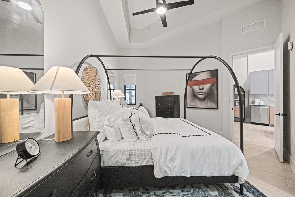 A modern bedroom with a large bed and a ceiling fan.