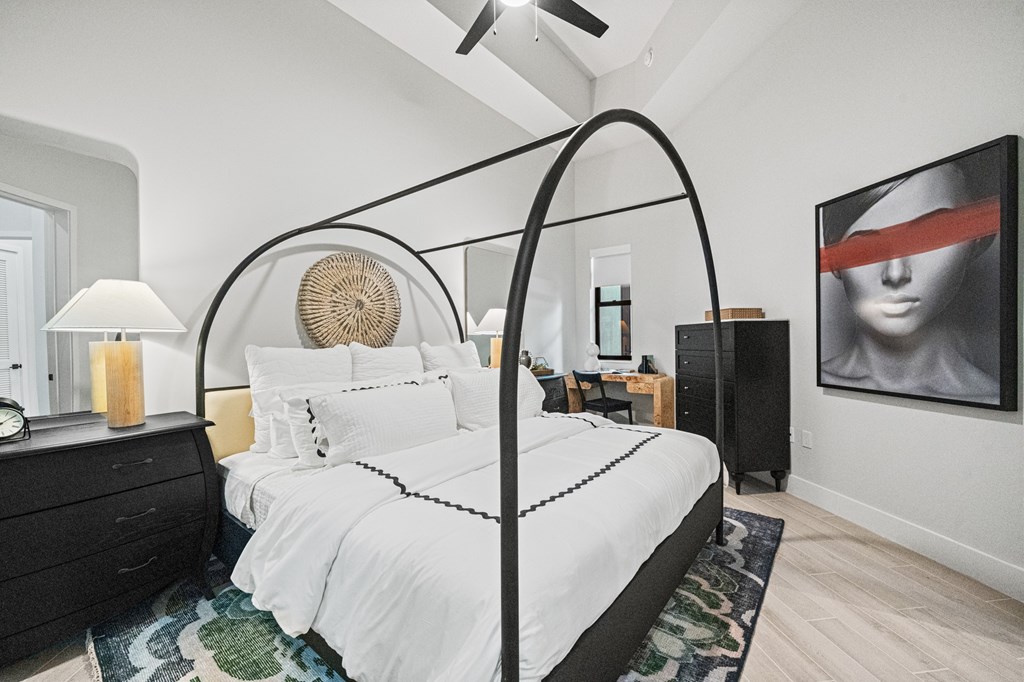 A bedroom with a white bed and a black canopy.