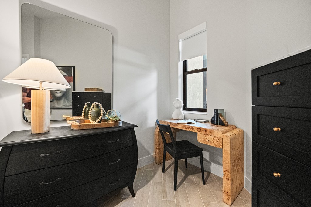 A black dresser with a wooden desk and chair in front of it.