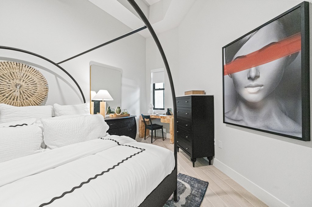 A bedroom with a large painting on the wall.