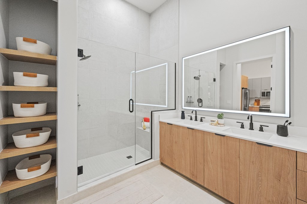 A bathroom with a walk-in shower, double sinks, and wooden shelves.