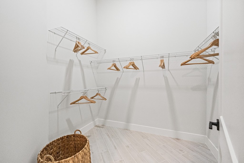 A room with clothes hanging on a rack and a basket on the floor.
