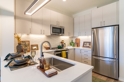 A modern kitchen with a stainless steel refrigerator and a white countertop.