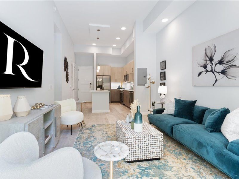 a living room with a blue couch and two white chairs